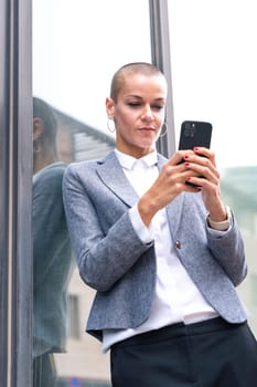 Satisfied with the results, the businesswoman walking on the street outside the office building, a mature boss holds a phone in her hands, writes messages and reads news online, using an app.