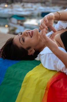 Smiling young woman with lgtbi flag fighting and showing strength out of pride. Concept: lifestyle, pride, outdoors