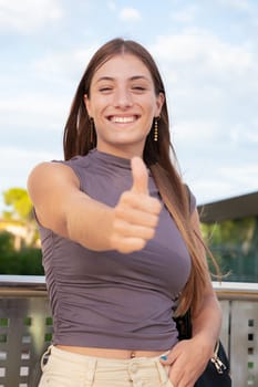 Close-up of happy teenage female student pointing thumb up. Facial expression of joy