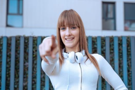 Young caucasian woman pointing her finger in front looking at the camera. Woman Showing Signs.