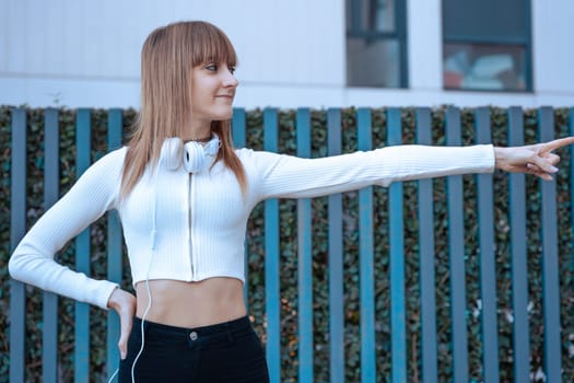 Young caucasian woman with headphones pointing to the side at logo. Woman Showing Signs