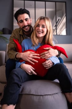 Young couple smiling with a giant heart looking At camera. Valentine's Day.