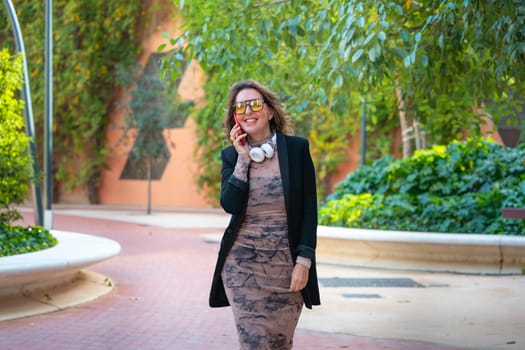 Beautiful middle-aged caucasian woman walking around the city having a conversation on cell phone.