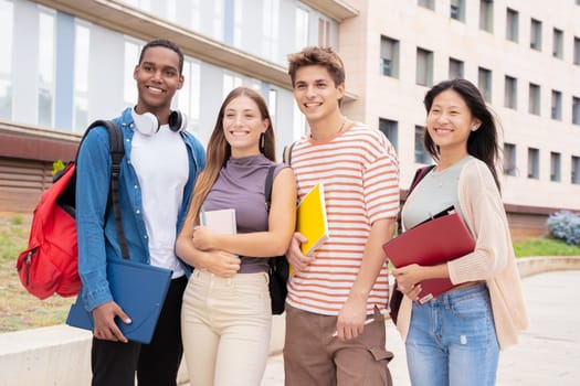 Happy group of college friends with notebooks in hand laughing making a selfie on campus. university life concept
