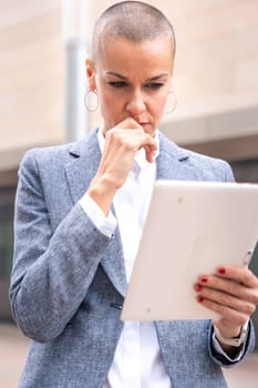 Thoughtful businesswoman with results of businesswoman walking down the street outside office building, a mature boss holds a phone in her hands, writes messages and reads news online, using an app.