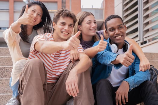 multiracial students meeting on campus with thumbs up looking at camera.concepts of youth, college life, adolescence and urban life