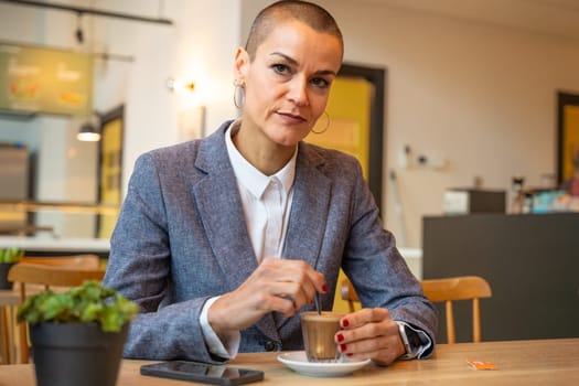 Business woman in a trendy cafe drinking coffee. Beautiful caucasian model posing for the camera.