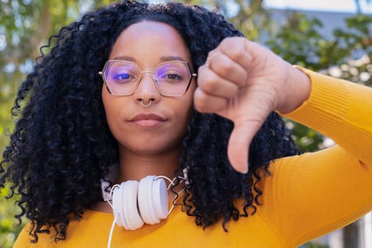 Close-up of pensive black woman pointing thumbs down.confident facial expression.