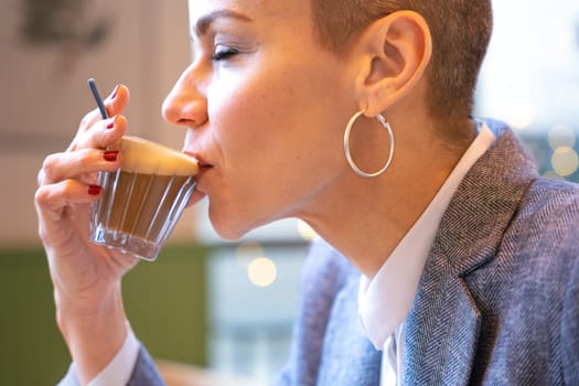 Side view Businesswoman in a trendy cafe drinking coffee. Beautiful Caucasian Model Reflections of the windows.