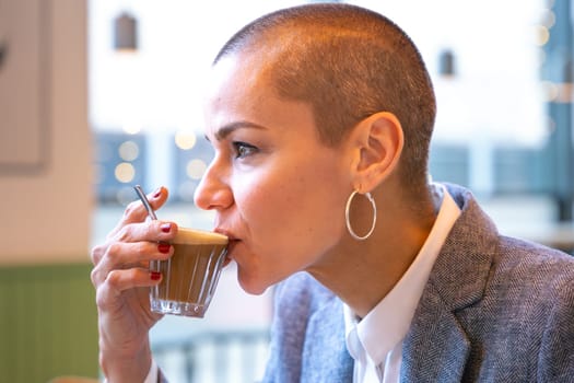 Businesswoman in a trendy cafe drinking coffee. Beautiful Caucasian Model Reflections of the windows.