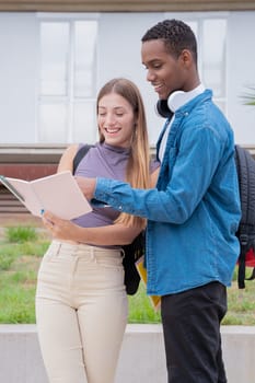 smiling multiracial college students outdoors preparing for exam.