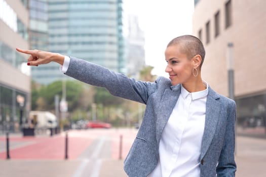 Confident middle adult pointing finger to the side of logo. Woman showing signs Smiling young woman pointing finger to the side