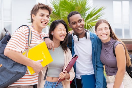 Happy group of college friends with notebooks in hand laughing making a selfie on campus. university life concept