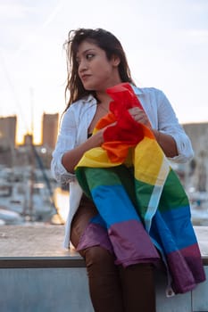 Smiling young woman with lgtbi flag fighting and showing strength out of pride. Concept: lifestyle, pride, outdoors