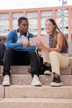 smiling multiracial college students sitting outdoors preparing for exam.