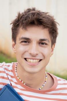 Caucasian student sitting on campus smiling looking at camera College life concept.