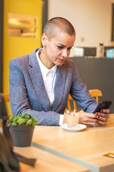 Businesswoman who takes a break in a cafe looks at the results with satisfaction. A mature boss holds a phone in her hands, writes messages and reads news online, using an app.