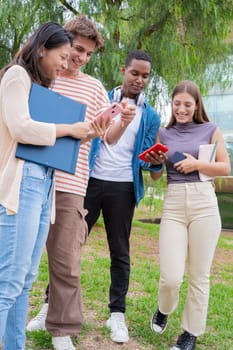 Group of friends using looking at their smartphones Multiracial teenagers browsing the internet with mobile phone on campus