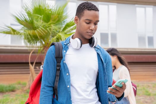 Young Black man using social media with smartphone app and wireless technology outdoors.