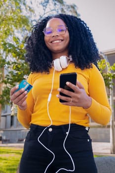 vertical photo happy black woman with credit card and smartphone in hands. Looking at camera. Concept: online store payment