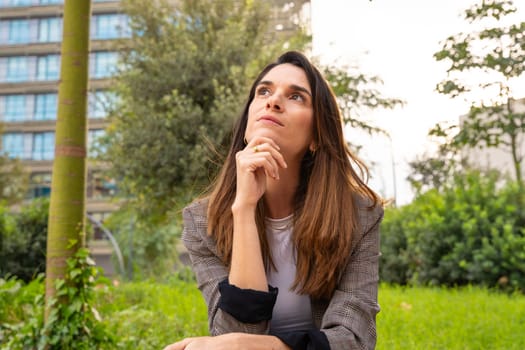 Thoughtful business woman with business woman results sitting on the street outside the office building, a mature boss staring into infinity with thoughtful face.
