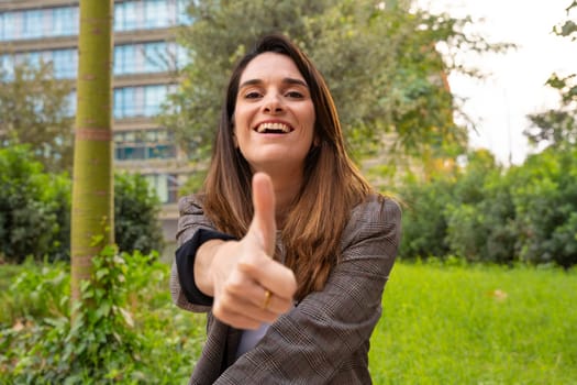Close-up of a happy young caucasian woman pointing with her thumbs up. Facial expression of joy.