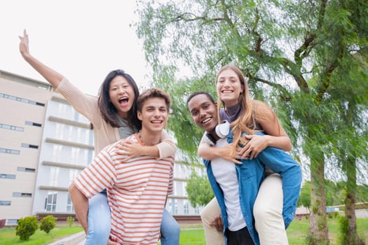Young students having fun carrying their friends with their arms raised looking at the camera.