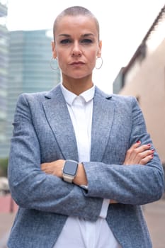 Close-up of a caucasian businesswoman looking seriously at the camera in a suit standing in outdoor workspace. Front view of a young lawyer with thoughtful expression staring