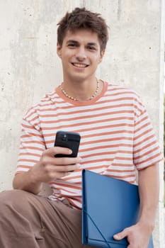 Happy student is inside the university campus using a social media app. College life