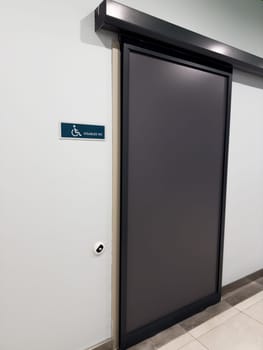 Vertical photography of slider entry door in handicapped restroom. Caring for disabled people for use of specialized toilet in building for people in wheelchair. Help with going to toilet for people