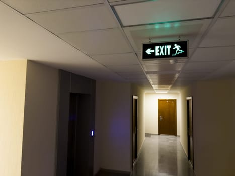 Sign on ceiling showing direction to emergency exits along stairs from burning building. Leaving building using emergency exits in case of emergency. Emergency exits from building with green sign