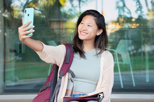 Happy young chinese taking a selfie with smartphone