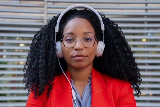 Thoughtful young woman with headphones looking at camera. Front view of a black woman Head shot of a proud businesswoman