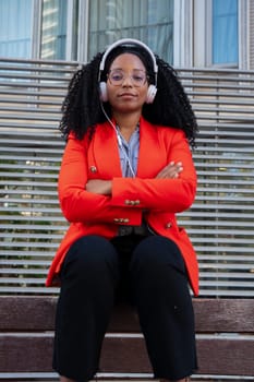 Thoughtful young woman with headphones looking at camera. Front view of a black woman with afro hair. Head shot of a proud businesswoman
