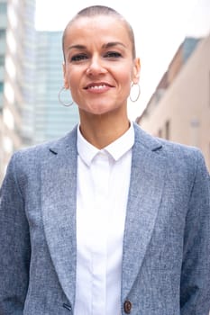 Close-up of a caucasian businesswoman looking happy at the camera in a suit standing in outdoor workspace. Front view of a young lawyer with thoughtful expression staring