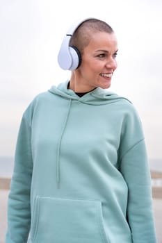 Portrait Fit woman smiling at camera with headphones on. Woman having fun during her morning workout.