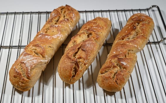 Three golden-brown loaves of bread rest on a cooling rack, filling the kitchen with a warm, inviting aroma.