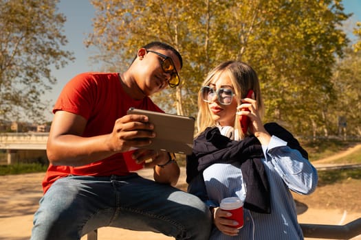 young man with sunglasses showing his friend a video on the digital tablet having fun an afternoon together in the park.