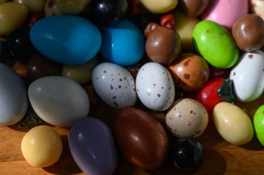 Vibrant collection of eggs in varying colors and patterns brightens up a wooden surface in springtime.