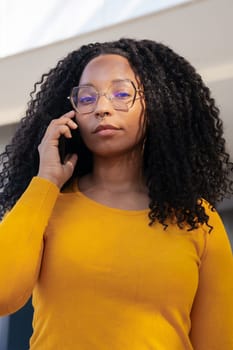 Beautiful black woman wearing blue sunglasses talks on the cellphone angry