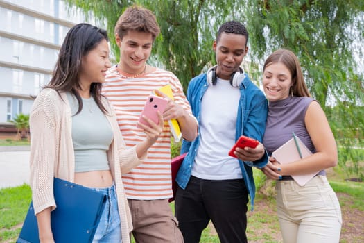Group of friends using looking at their smartphones Multiracial teenagers browsing the internet with mobile phone on campus