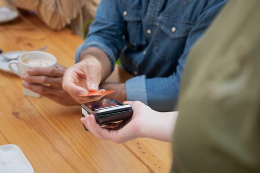 Hand of a young man holding a credit card and making a payment transaction.