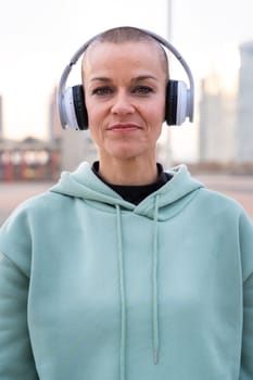 Close-up Fit woman smiling at camera with headphones on. Woman having fun during her morning workout.