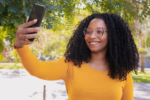 Beautiful black woman with glasses happy taking a selfie with the cell phone.
