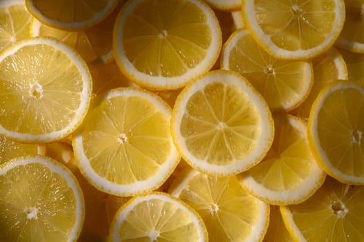 Juicy lemon slices lay flat, showcasing their bright yellow color and inviting freshness, perfect for a summer drink.