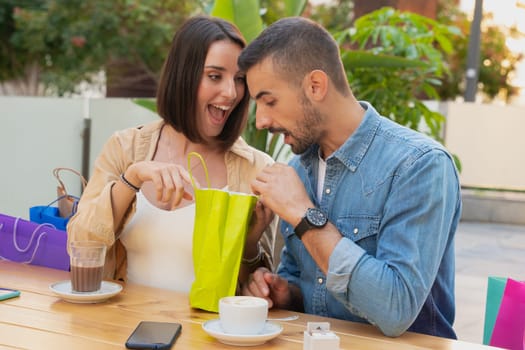 sale, shopping, consumerism, leisure and people concept - happy couple with shopping bags drinking coffee at shopping center
