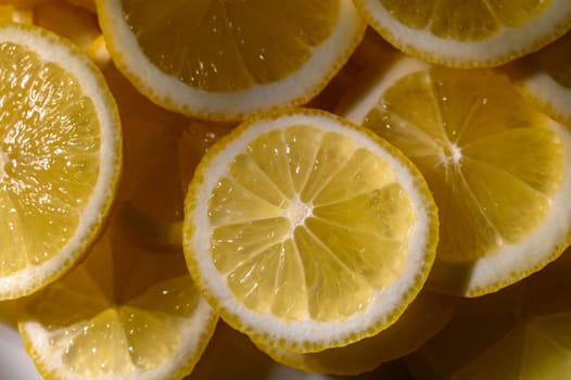 Juicy lemon slices are beautifully layered, showcasing bright yellow hues and inviting freshness in a sunlit space.