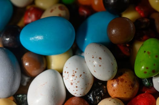 Decorative eggs in pastel colors rest among bright candy pebbles, evoking a festive spring atmosphere for gatherings.