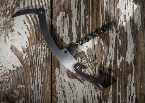 A beautifully crafted corkscrew lies elegantly on weathered wood, evoking a sense of warmth and nostalgia.