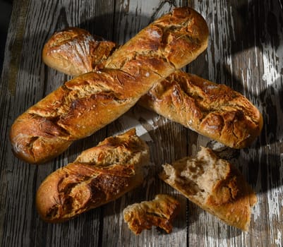 Golden crusted loaves of artisan bread sit on a weathered wooden surface, highlighting their texture and warmth.